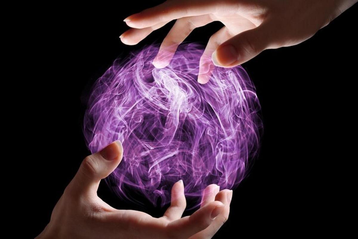 a pair of hands holding a purple ball of electricity