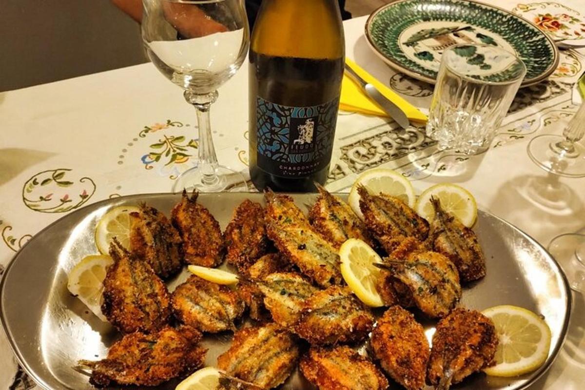 Un plato de pollo con limones y una botella de vino.
