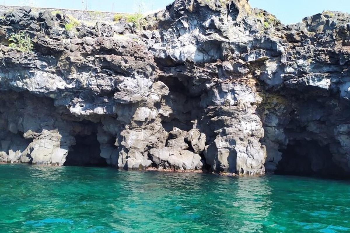 a rocky cliff with green water in front of it