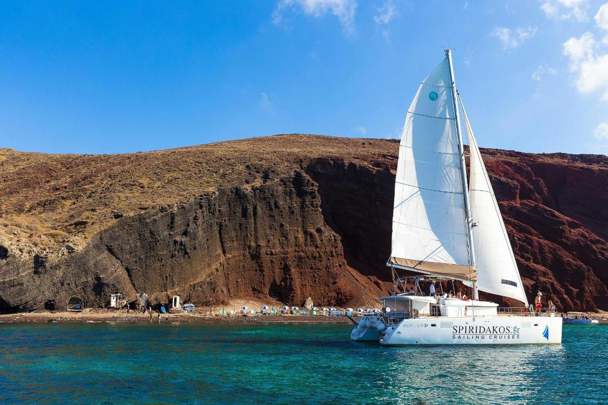 a white sail boat in the water near a mountain