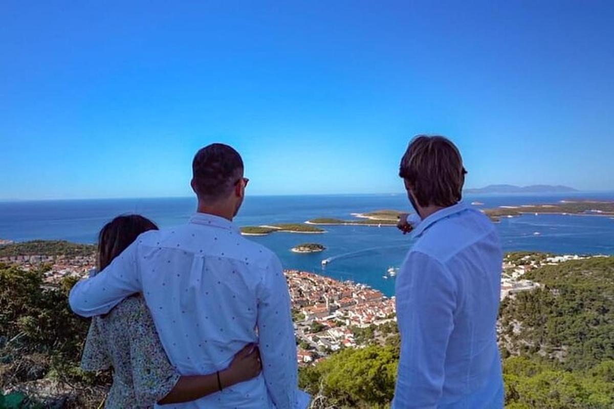 kolm inimest seisavad mäe otsas ja vaatavad ookeani