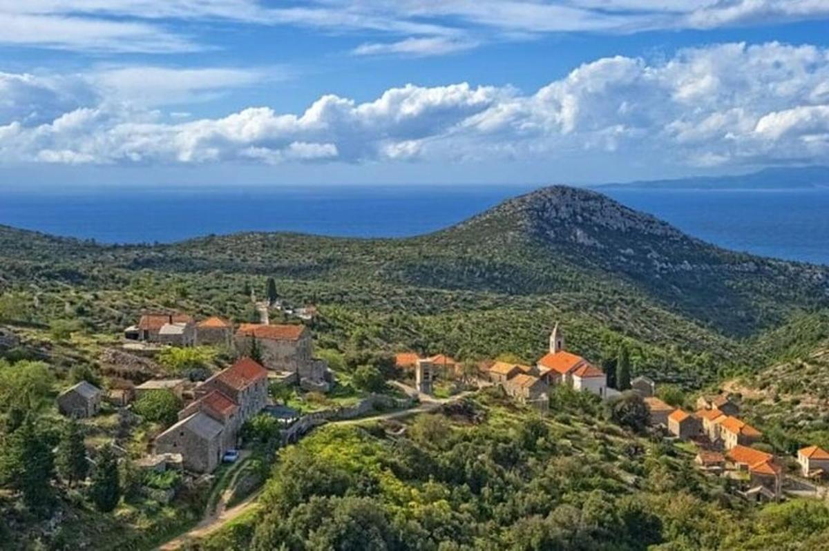 un villaggio su una collina con l'oceano sullo sfondo