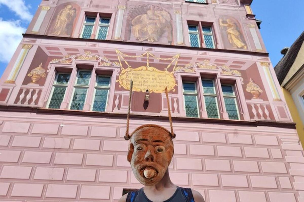 en person som står foran en rosa bygning med maske