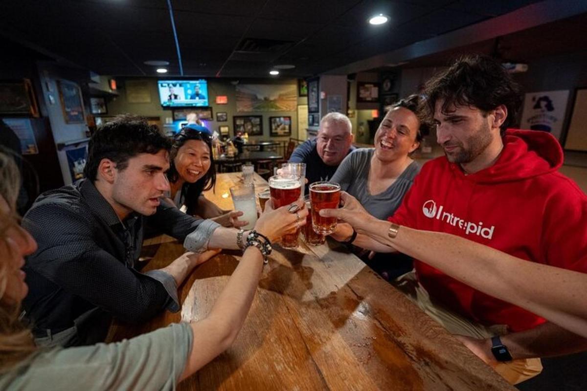 Un grupo de personas sentadas alrededor de un bar bebiendo cerveza.