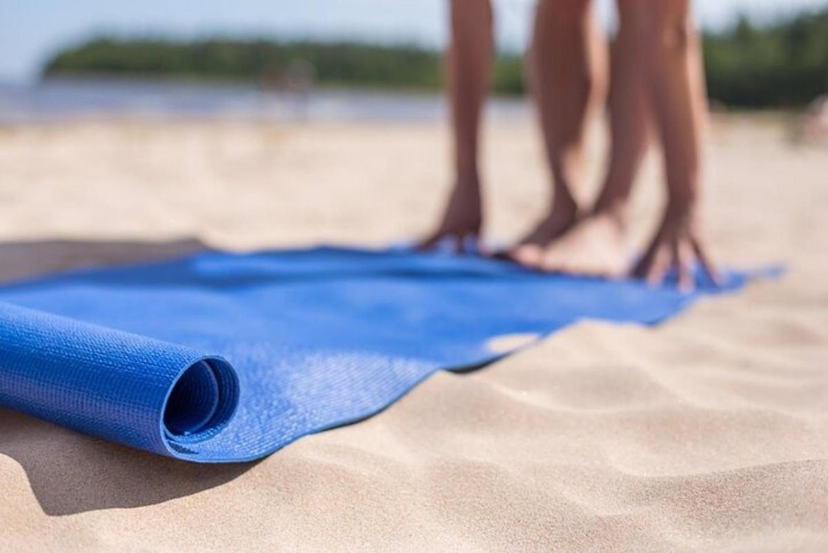 a blue beach towel on the sand with people on the beach