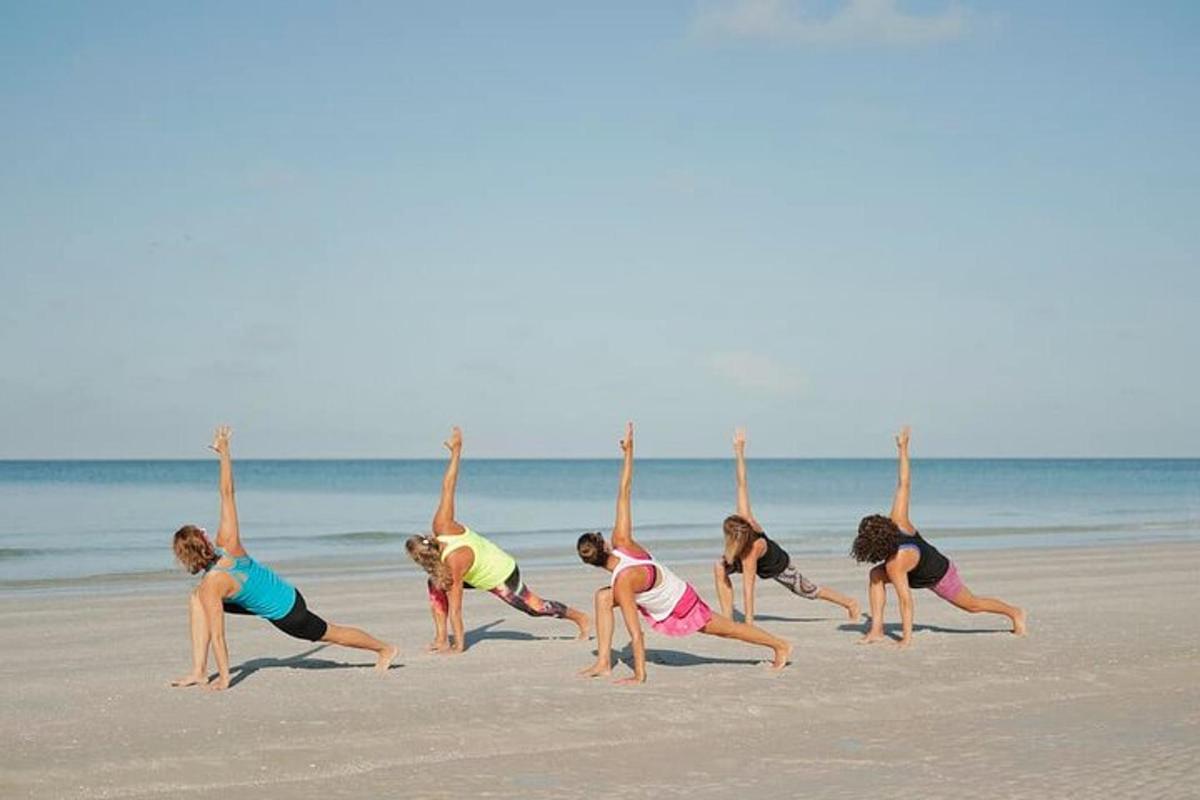 a group of women doing yoga on the beach