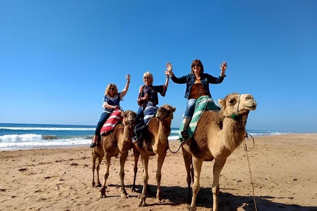 un gruppo di persone a cavallo di cammelli sulla spiaggia
