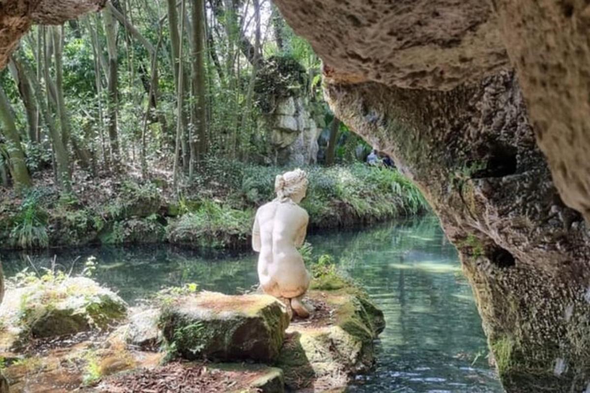 a statue sitting on a rock in a river