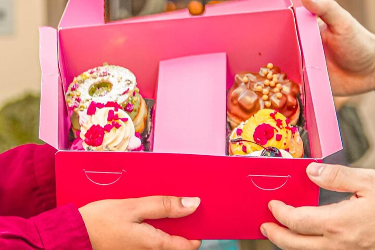 un enfant tenant une boîte rose de beignets
