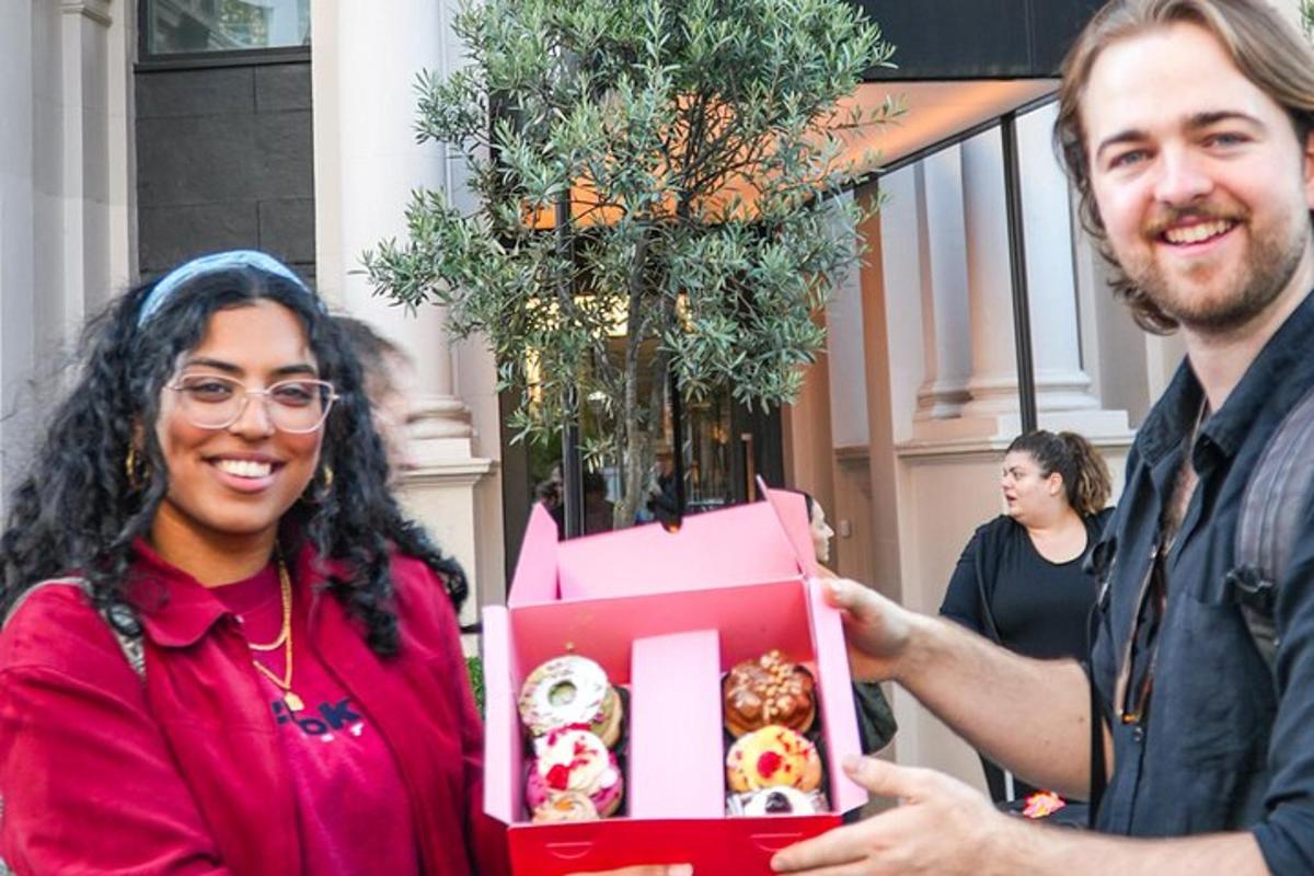 um homem entregando uma caixa de donuts a uma mulher