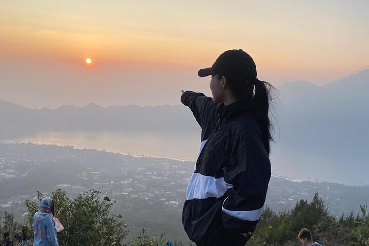 žena stojící na kopci a dívající se na západ slunce