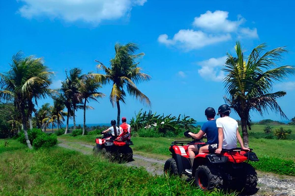 Un grupo de personas viajando en vehículos todo terreno por un camino de tierra.