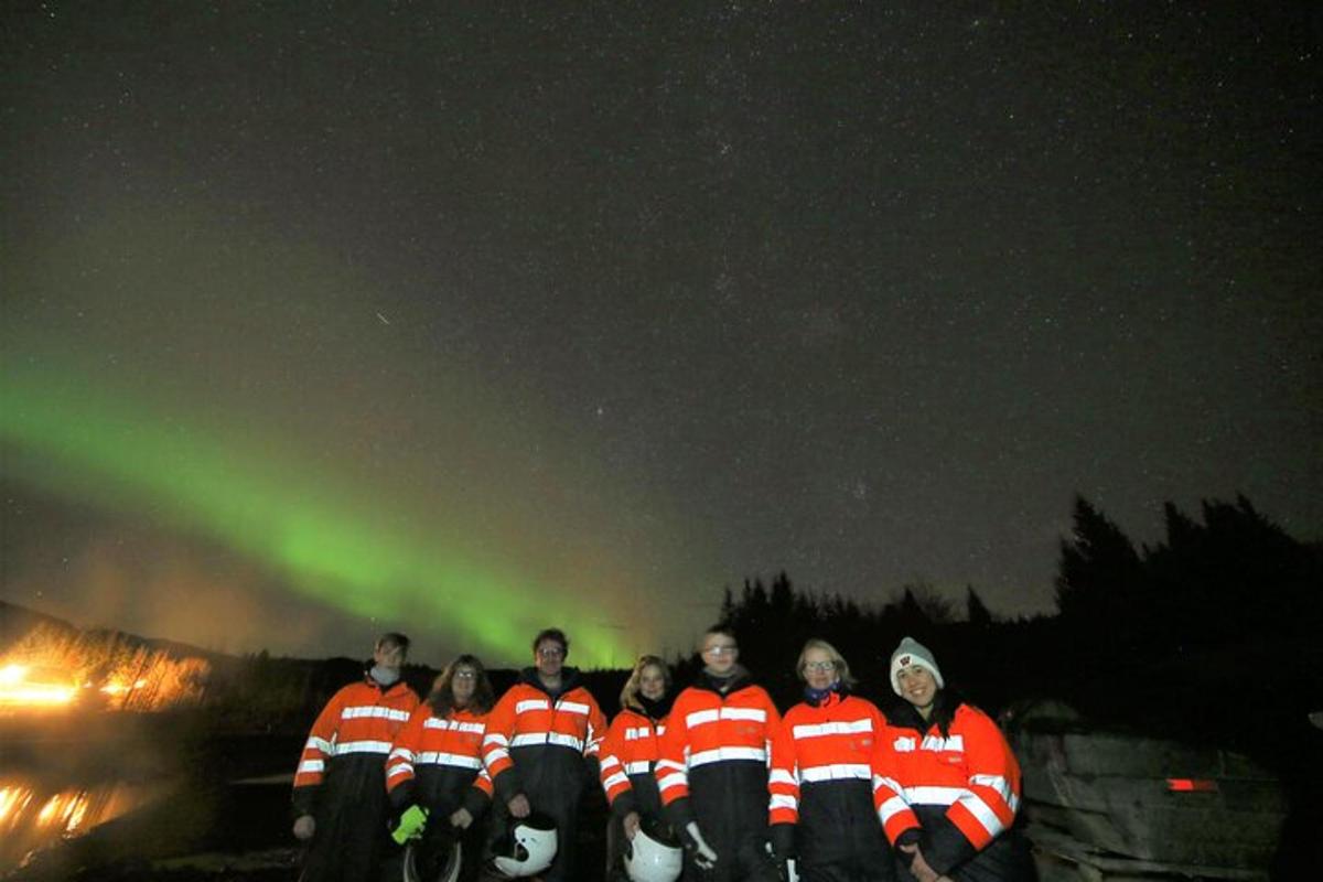 un groupe de personnes debout devant les aurores boréales