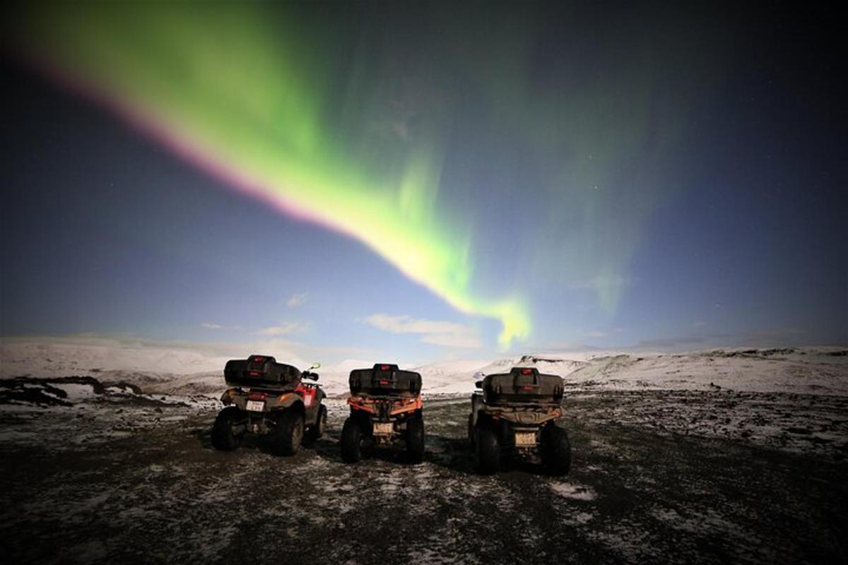 trois véhicules à quatre roues garés dans la neige avec l'aurore dans le ciel