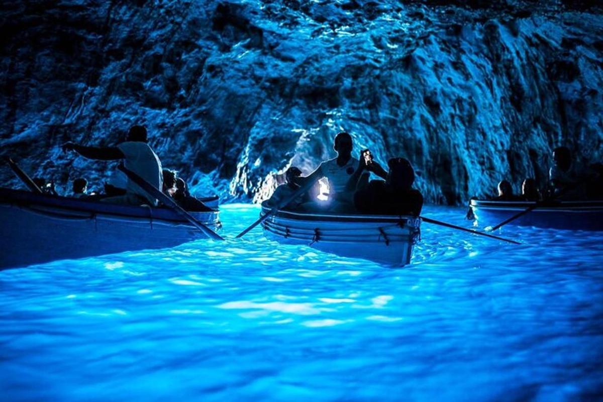 Un grupo de personas en botes en una cueva azul.