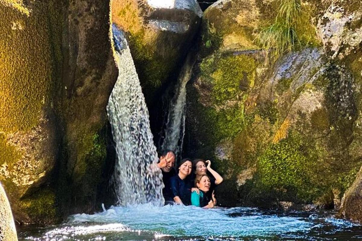 two people standing in the water in a waterfall