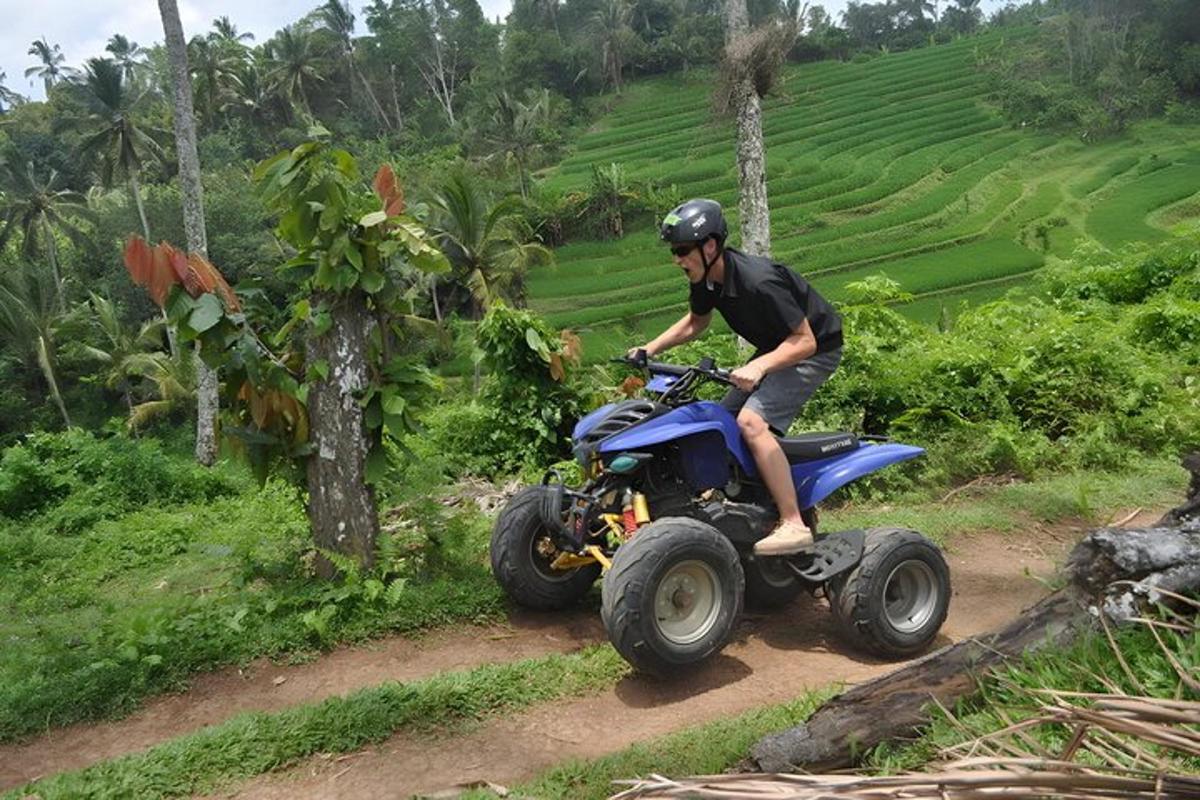 seorang pria mengendarai sepeda quad di jalan tanah