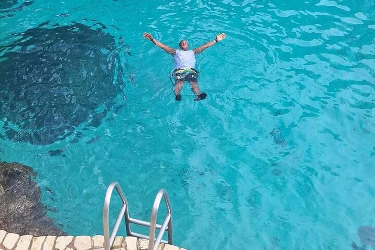 un home nedant en una piscina d'aigua blava