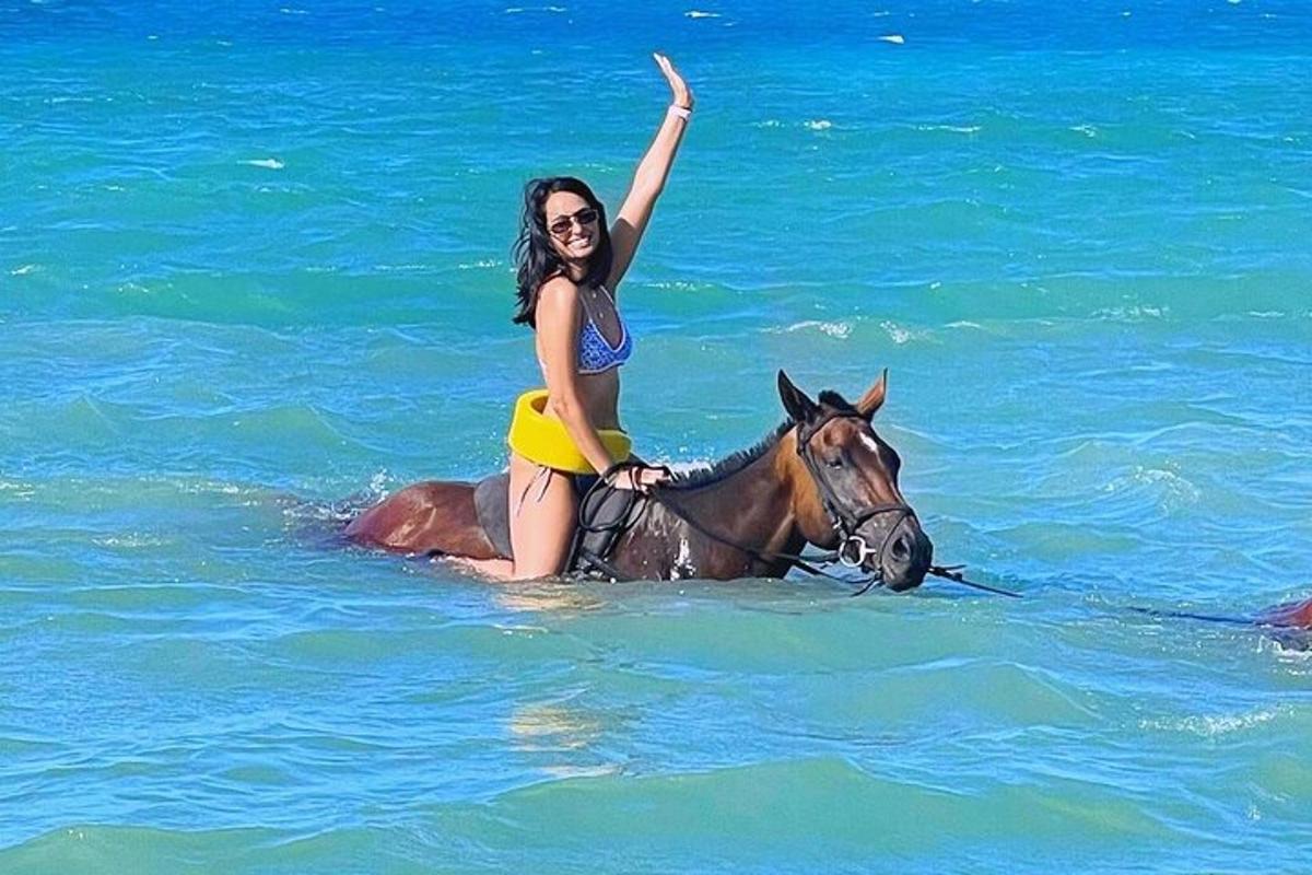 uma mulher cavalgando um cavalo no oceano
