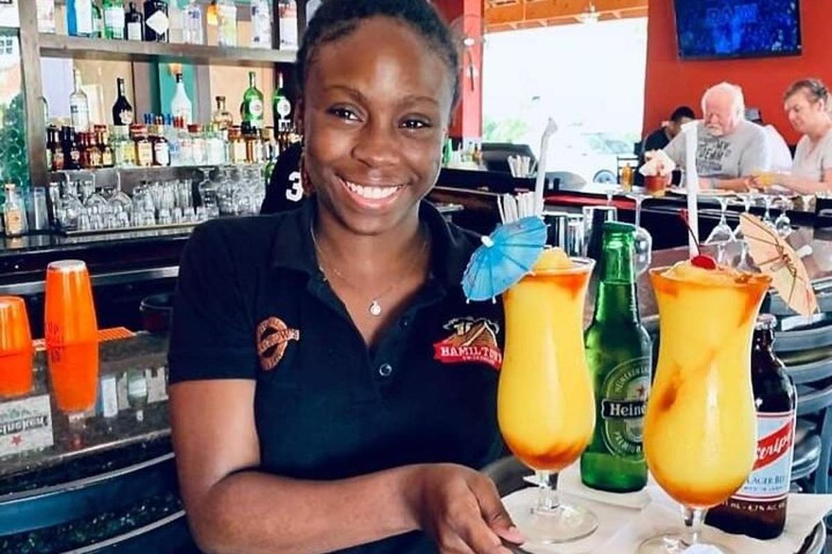 Una mujer sentada en un bar con dos cócteles.