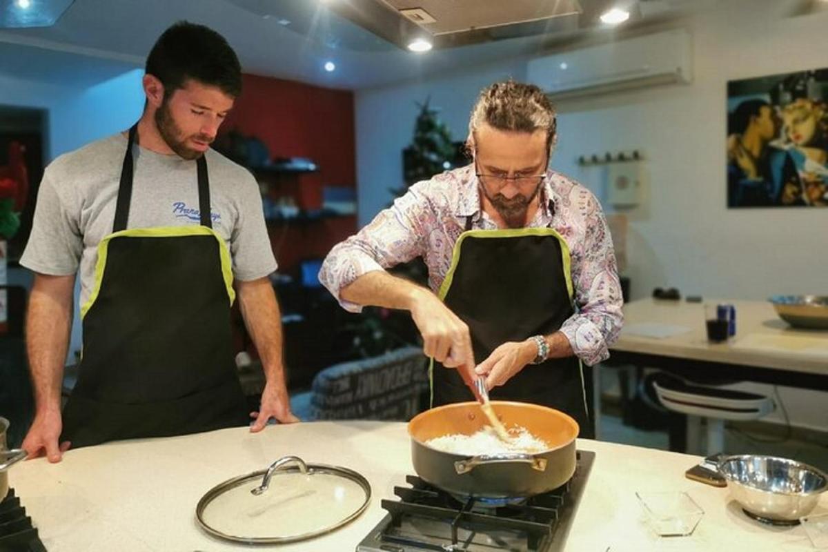 dvaja muži v kuchyni pripravujú jedlo na panvici