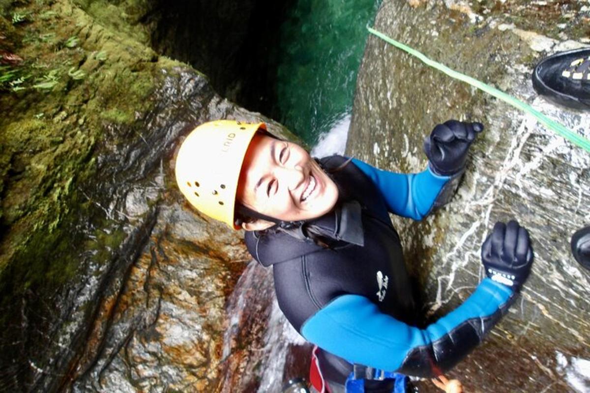 a woman is climbing a rock in a waterfall