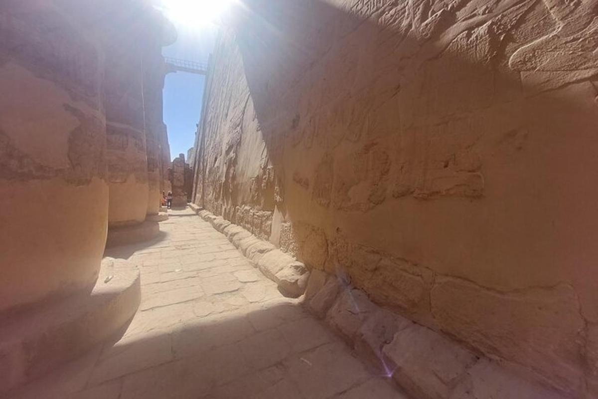 un vicolo con il sole che splende attraverso un muro di pietra
