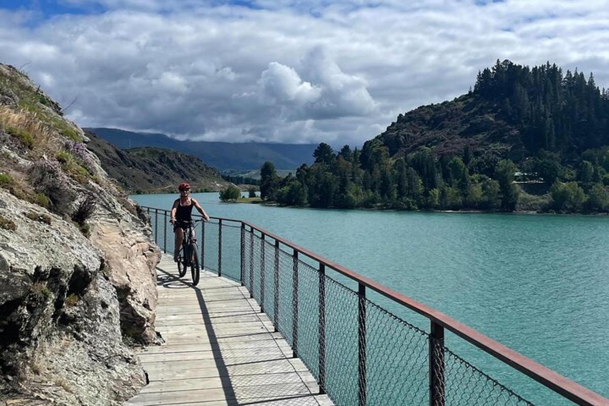 una persona montando en bicicleta en un puente sobre un lago