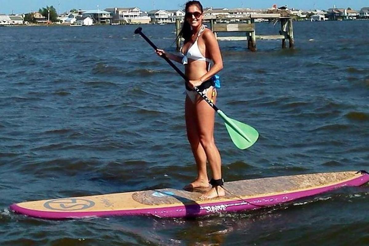 a woman in a bikini standing on a paddle board