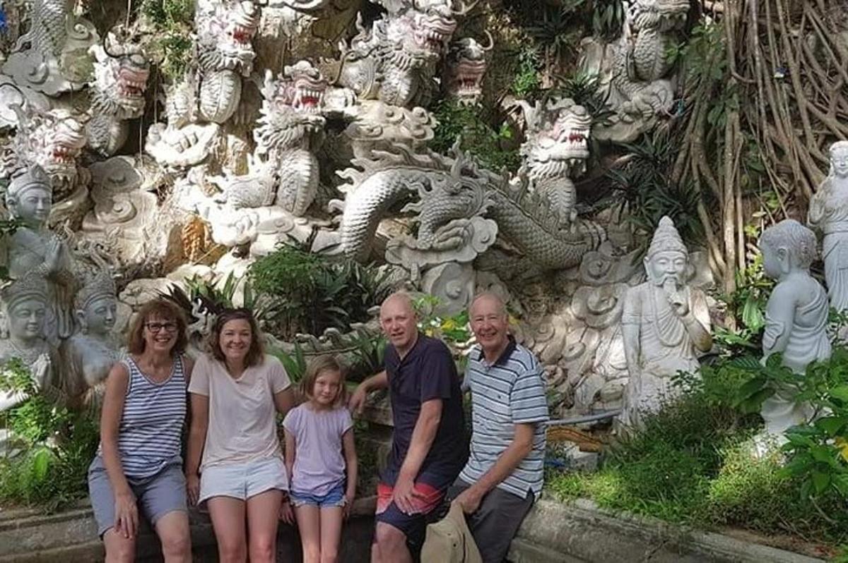 a family posing in front of a wall of statues