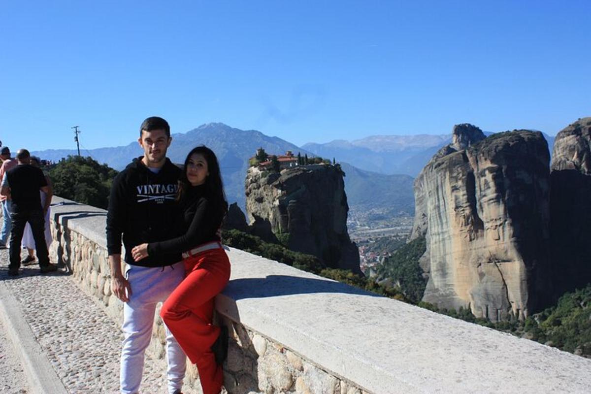 a man and a woman sitting on a wall at the mountain