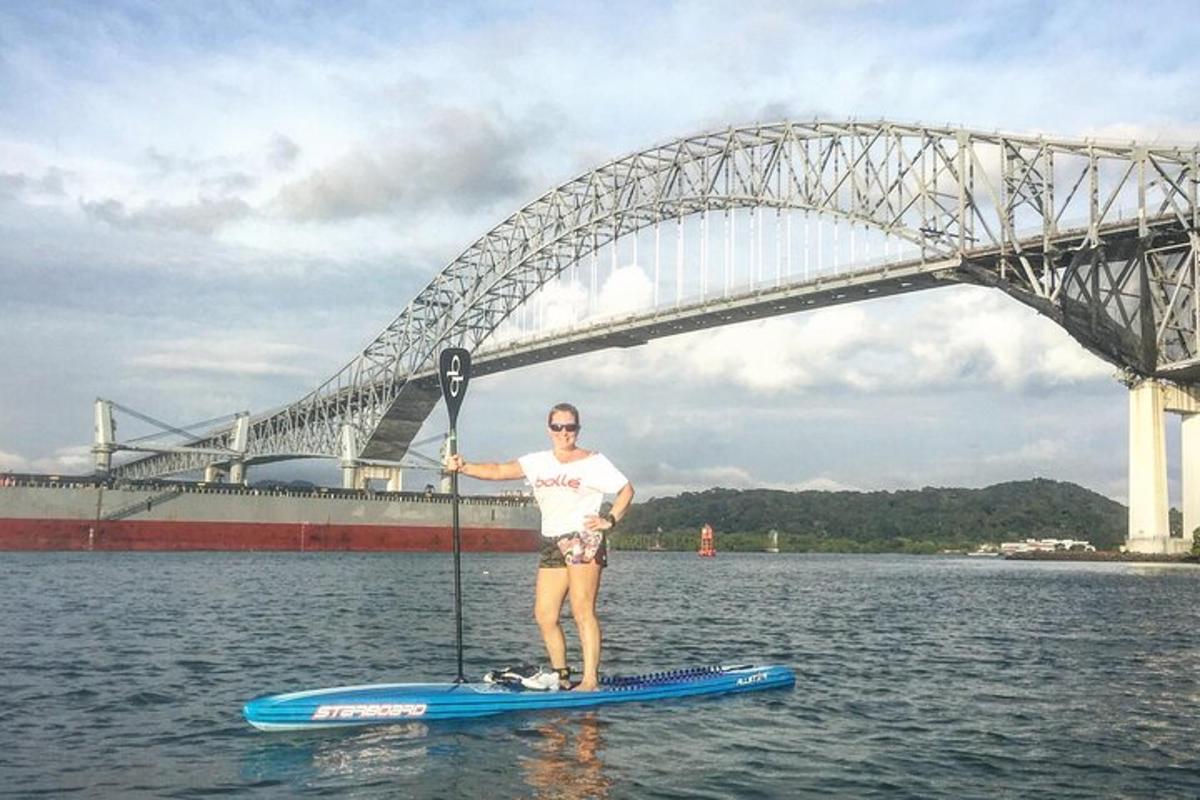 muž na paddleboardu ve vodě před mostem