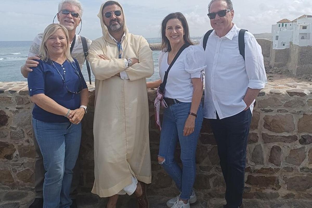 um grupo de pessoas em pé em um muro perto do oceano