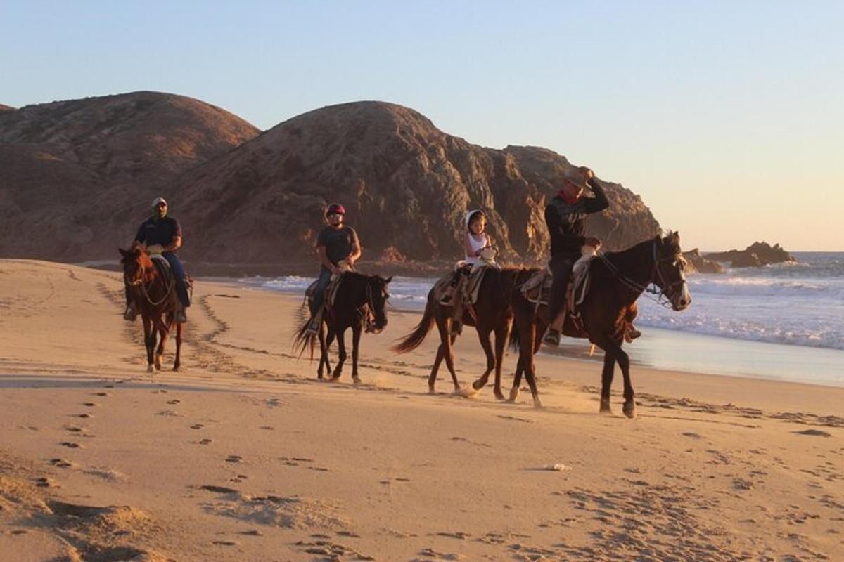 un grup de persones muntant a cavall a la platja