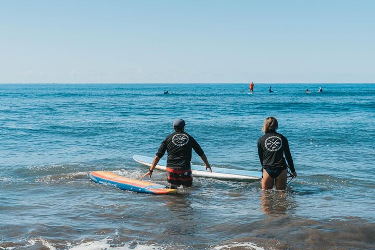 dva lidé stojící v oceánu se svými surfovými prkny