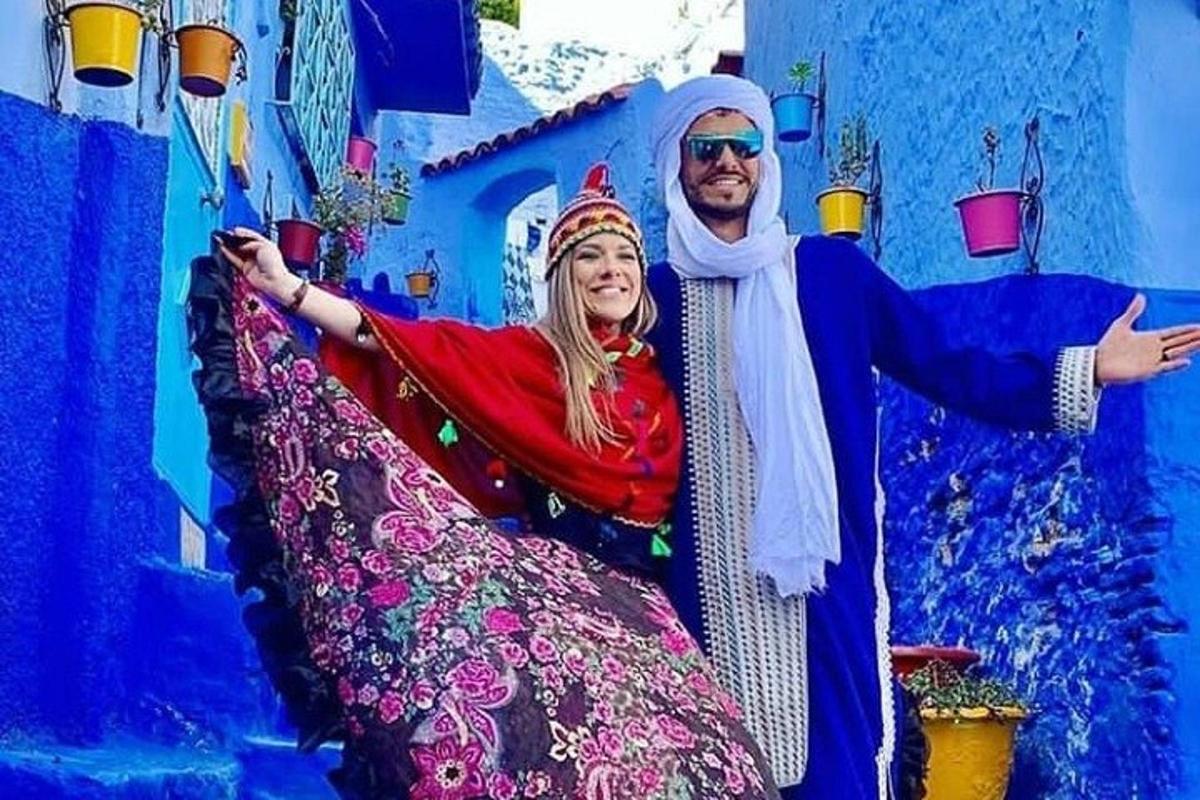 Un hombre y una mujer posando frente a un edificio azul.