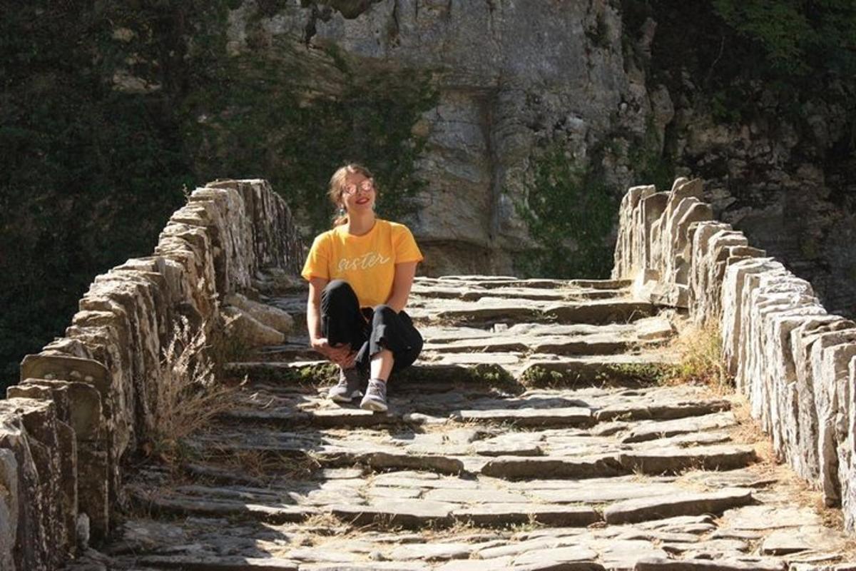 a young man sitting on a stone wall