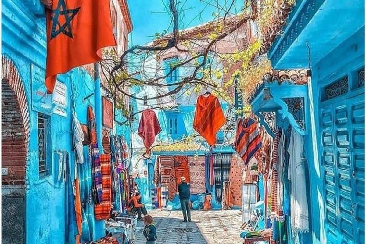 uma pintura de um prédio azul com pessoas caminhando por uma rua
