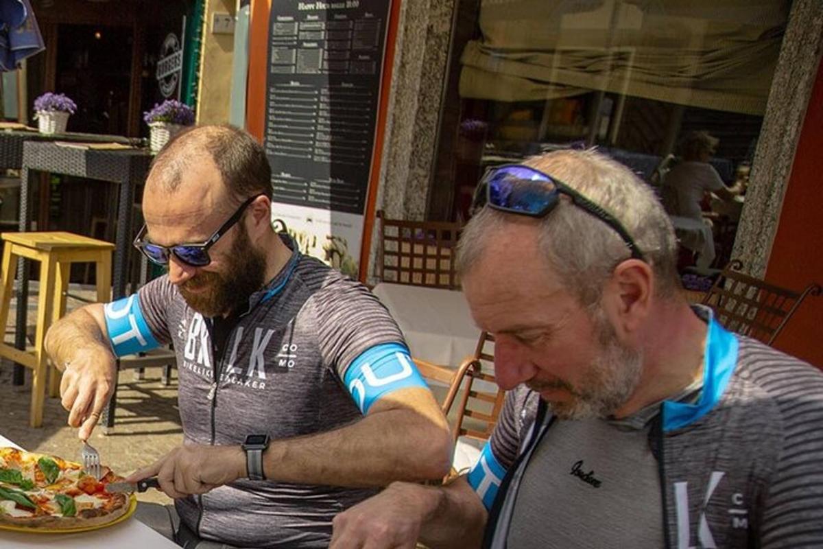 Dos hombres sentados en una mesa comiendo un plato de comida