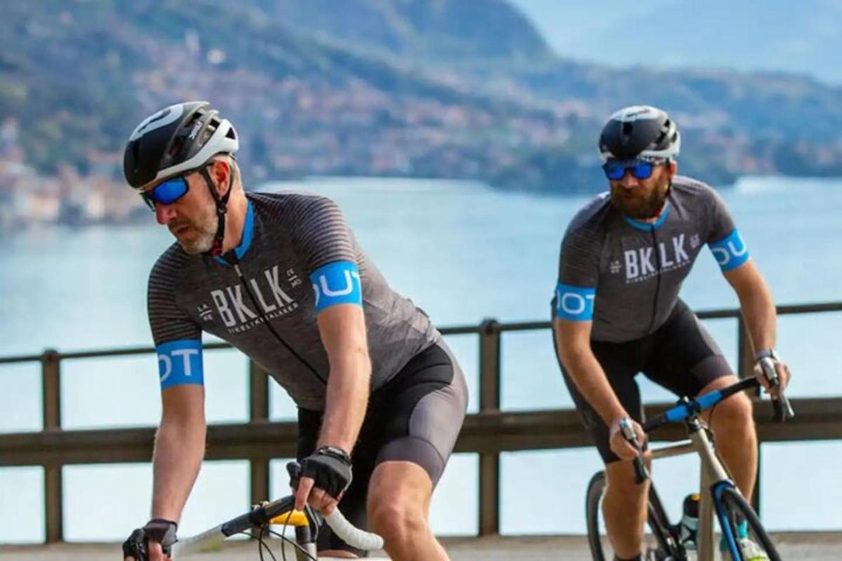 Dos hombres andando en bicicleta en un puente cerca del agua