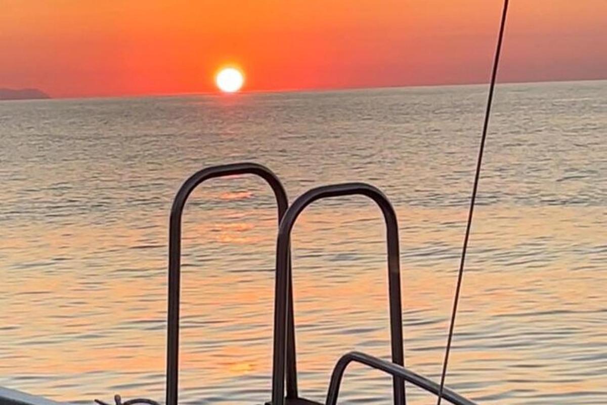 loď v oceánu se západem slunce v pozadí