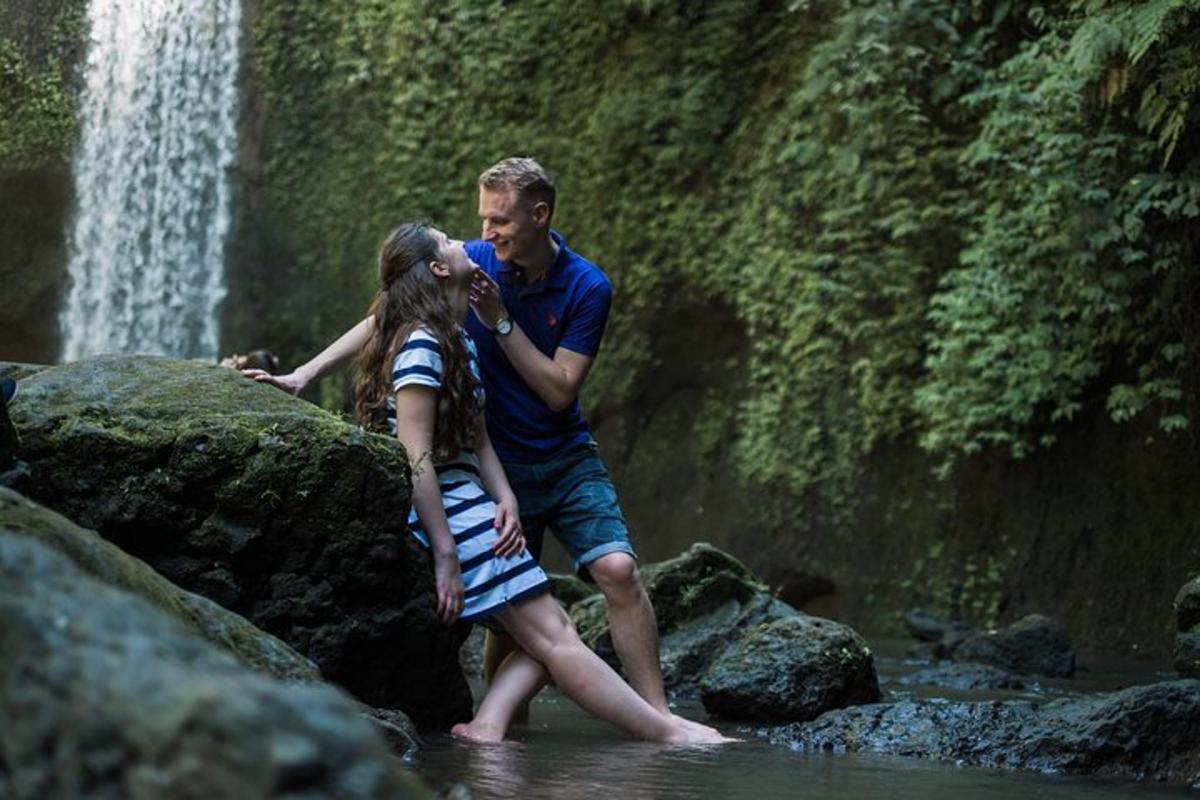 a man and a girl standing on rocks near a waterfall