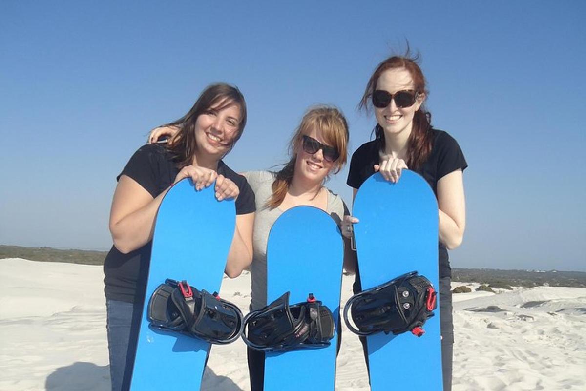 Skupina tří žen držících snowboardy na pláži
