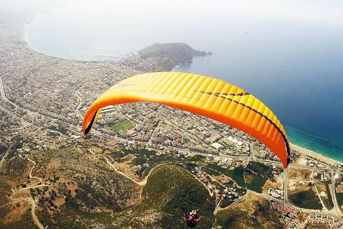 Žlutý a oranžový padák letící nad oceánem