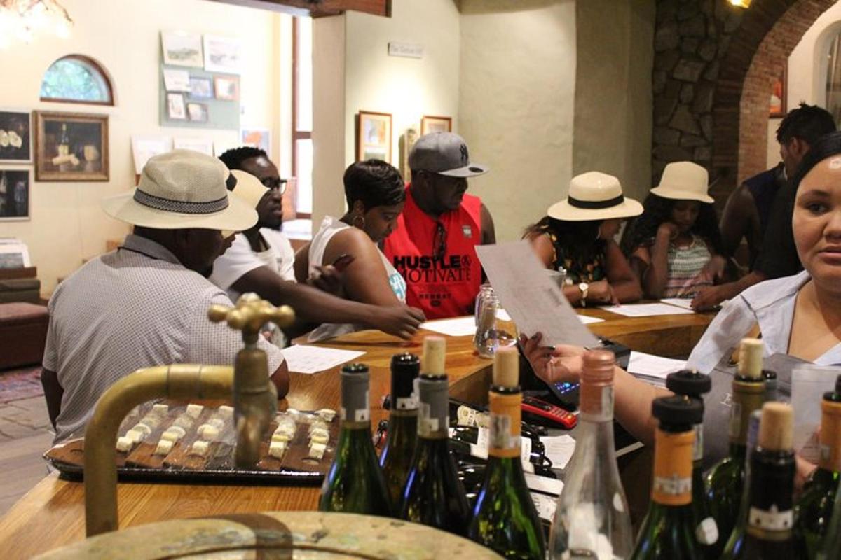 Un grupo de personas sentadas alrededor de una mesa con botellas de vino.