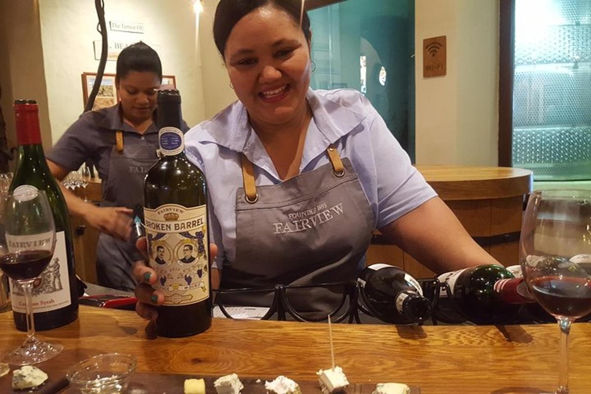 Una mujer sosteniendo una botella de vino sobre una mesa.