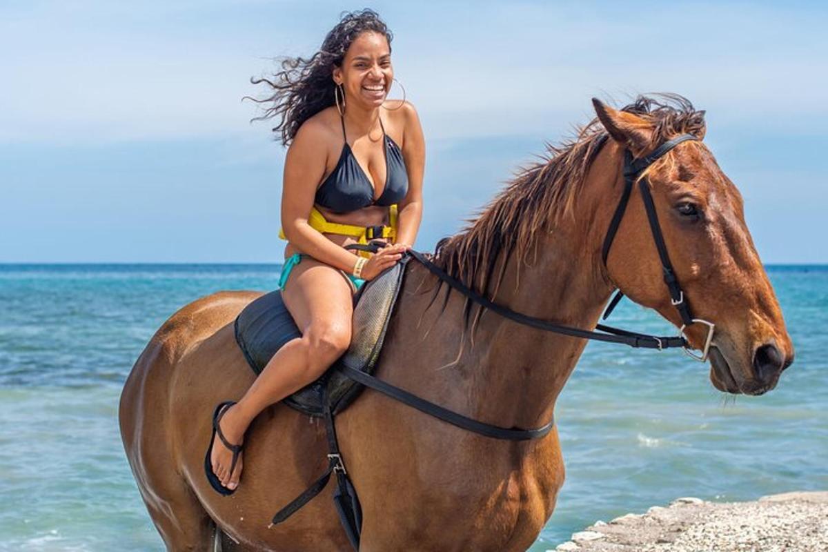 una donna in bikini a cavallo sulla spiaggia
