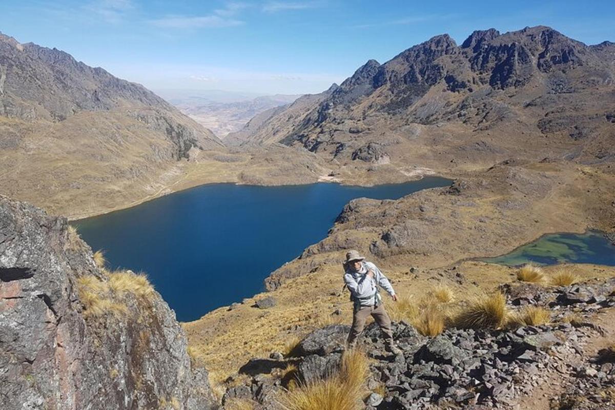 Ein Mann steht auf einem Berggipfel und blickt auf einen See