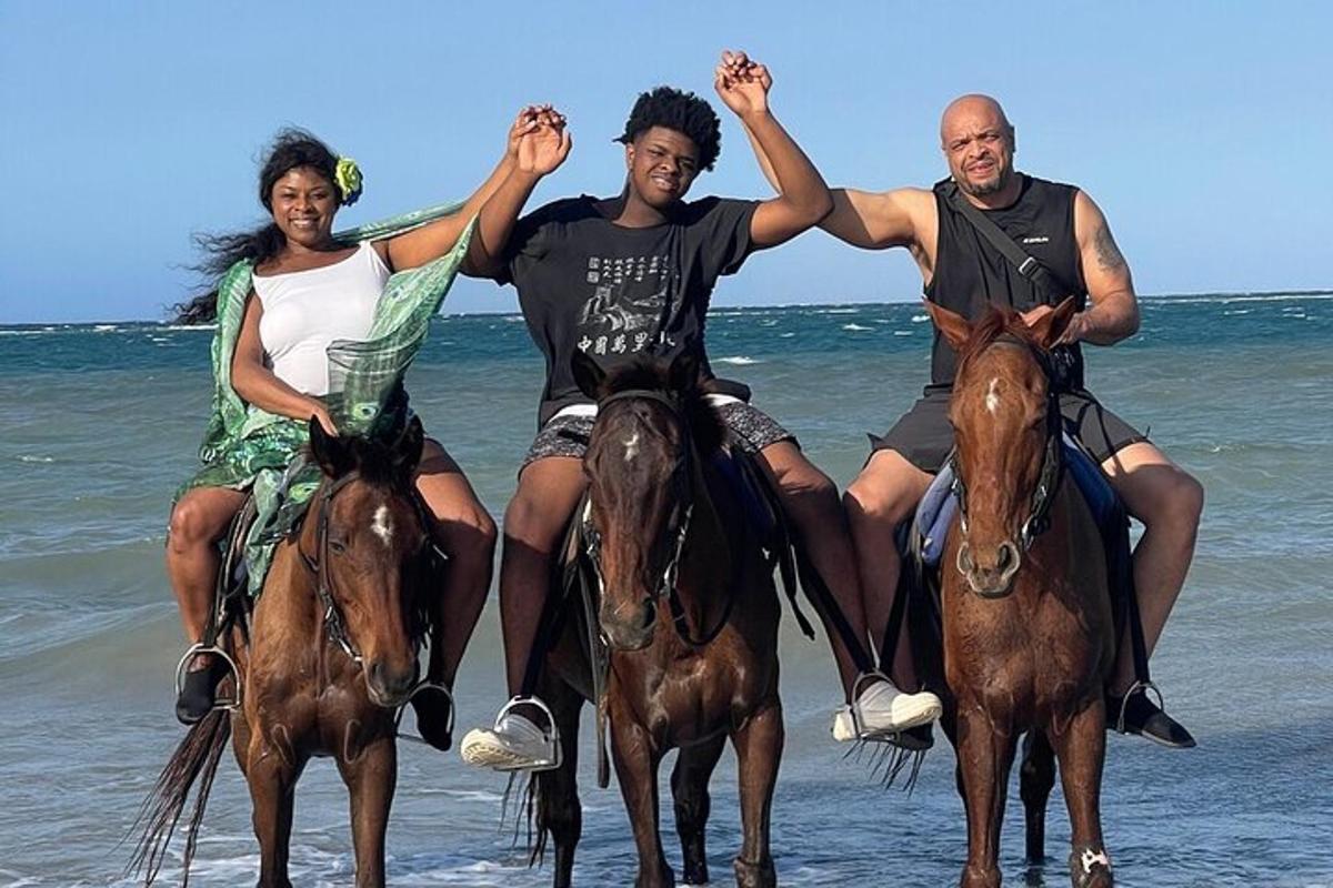un gruppo di tre persone a cavallo sulla spiaggia