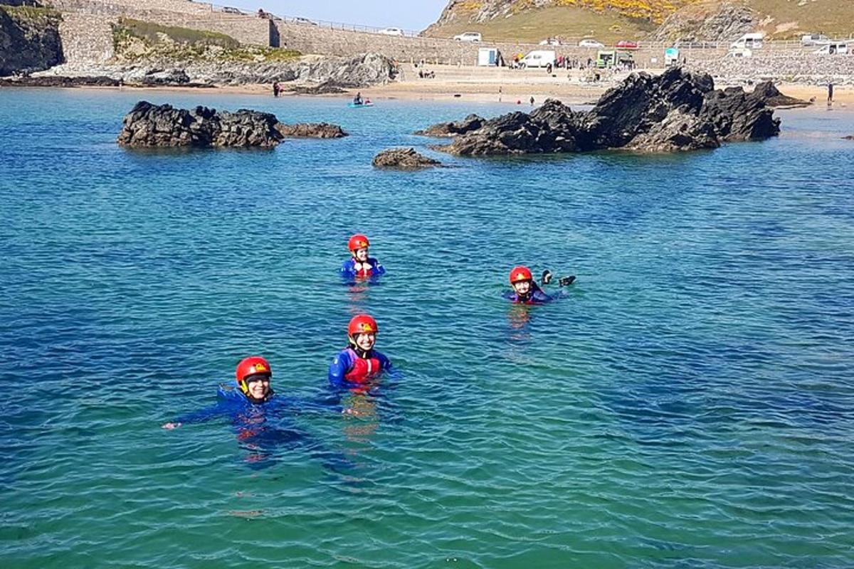 tiga orang sedang berenang di dalam air berhampiran pantai